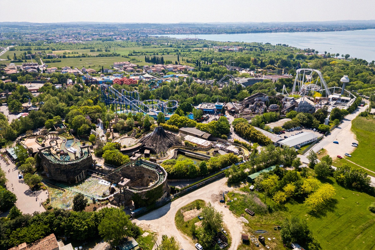 Luftbild des Gardaland Park mit Achterbahnen und dem Gardasee im Hintergrund